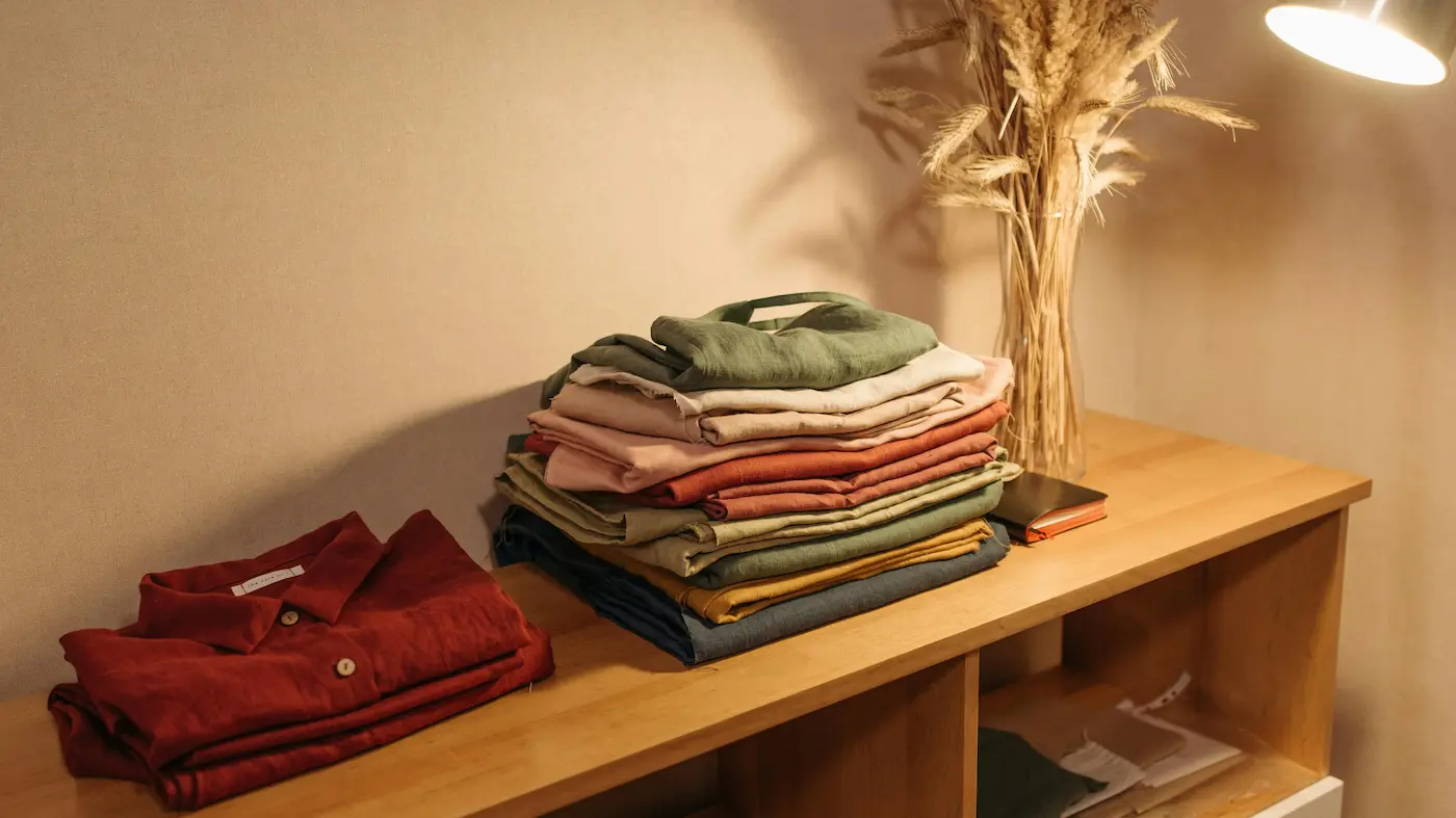 Pile de vêtements en lin pliés sur une étagère éclairée pas une lampe